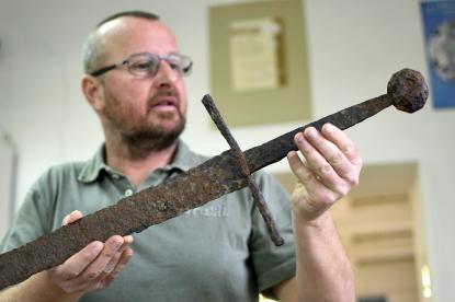 Kertész Róbert régész egy másfélkezes vaskardot vizsgál a szolnoki Damjanich János Múzeumban