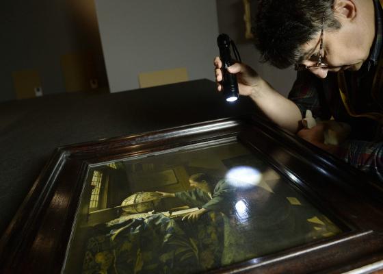 Fáy András, a Szépművészeti Múzeum Restaurátori Főosztályának vezetője nézi Johan Vermeer: Az asztronómus című, a Louvre-ból érkezett festményét.